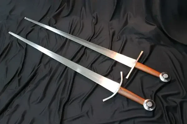 2 Kvetun arming swords. One with a straight crossguard, another with a curved crossguard.
